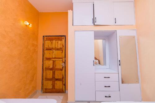 a room with white cabinets and a mirror and a door at Dondoo's Paradise- Perfect Vacation Home in Kilifi