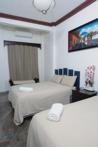a bedroom with two beds and a tv on the wall at Hostal Casa de Grethel in Flores
