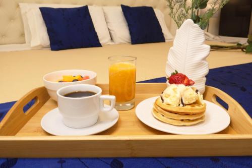 a tray with pancakes and a cup of coffee and a drink at Rig Vêda Hotel in Lima