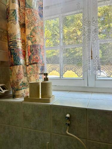 a bathroom with a window and two candles on a counter at Ana Marija Apartment - Vila Golf in Rogaška Slatina