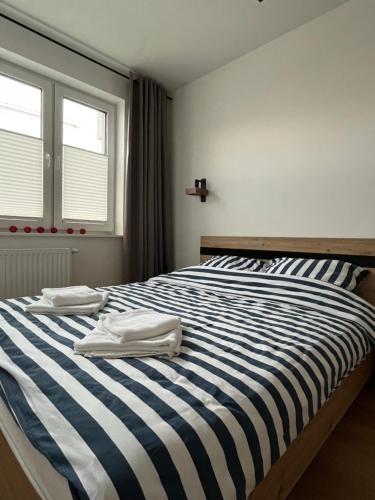 a bedroom with a striped bed with two towels on it at Apartament No1 Koszalin z bezpłatnym parkingiem podziemnym-faktura, Netflix in Koszalin