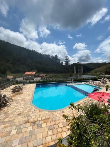 a large swimming pool with blue water in a resort at Apto Itaipava 5 min do Centro e Parque de Eventos in Itaipava