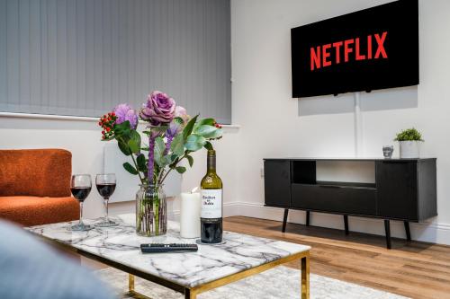 a living room with a table with a bottle of wine and flowers at Stylish 2BR 2BA Flat in Gravesend Sleeps 4 in Gravesend