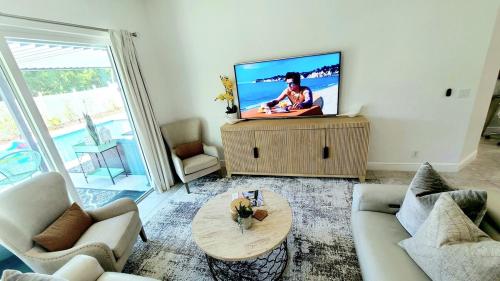 a living room with a flat screen tv on a table at PoshPadz Pool Villa, Hot Tub, Near Beach, Sleeps 6 in Jupiter