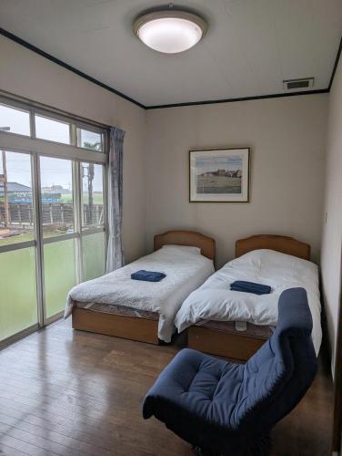 two beds in a room with a large window at Kenny's house in Joso