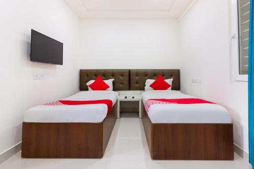 2 bedden met rode kussens in een kamer bij Super Hotel O Qualia Inn Kondapur Near Botanical Garden in Hyderabad