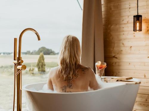 a woman sitting in a bath tub with a window at HACIENDA & Królicza Nora in Zatory