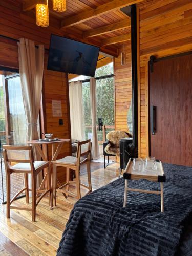 a living room with a television and a table and chairs at Cabanas nascer do sol - Encantada in Alfredo Wagner