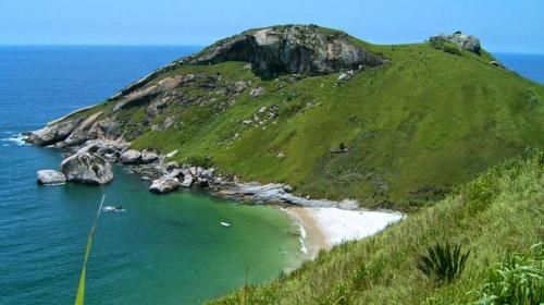 a small island in the ocean next to a beach at Suite Brisa 201 in Pedra de Guaratiba