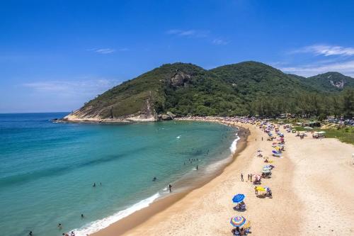 a beach with a bunch of people and the ocean at Suite Brisa 201 in Pedra de Guaratiba