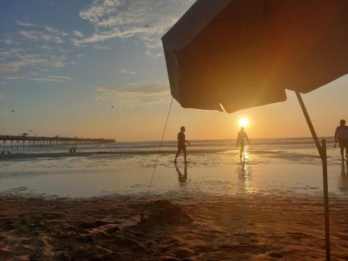 a group of people walking on the beach at sunset at Pimentel frente al muelle con balcón in Pimentel