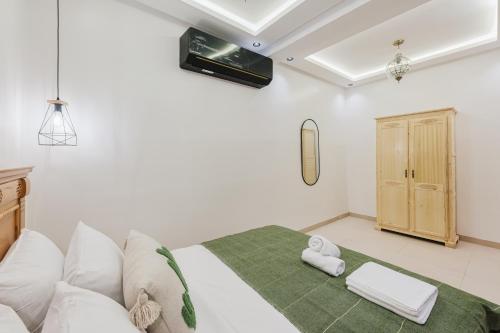 a bedroom with a white bed with a green blanket at Maison Joudia in Marrakech