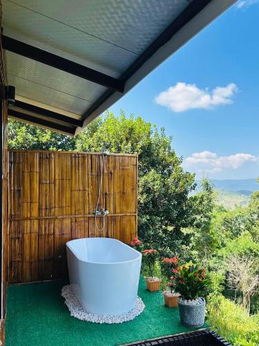a bath tub sitting on a patio with plants at บ้านสวนเอลเลน Ellen Farmhouse in Ban San Pu Loei