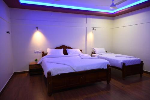 ThandikudiHasvika Hilltop Resort and Hotel的一间卧室配有两张带白色床单和灯具的床。