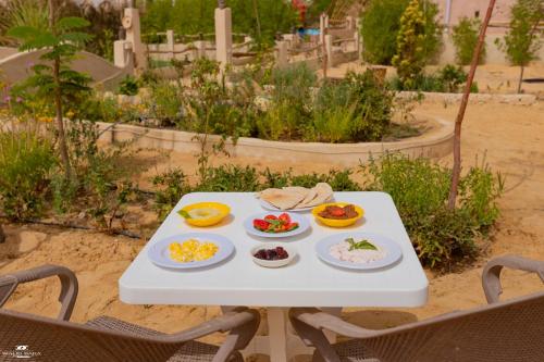 a white table with plates of food on it at Gagal House in Siwa