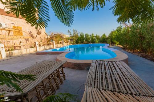 a swimming pool with benches in front of a house at Gagal House in Siwa