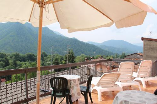 un patio con sillas, una mesa y una sombrilla en B&B Edelweiss, en Castione della Presolana