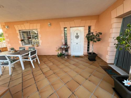 patio con mesa, sillas y puerta blanca en Villa Loli, Quiet villa with pool, next to beach and city, en Grao de Castellón