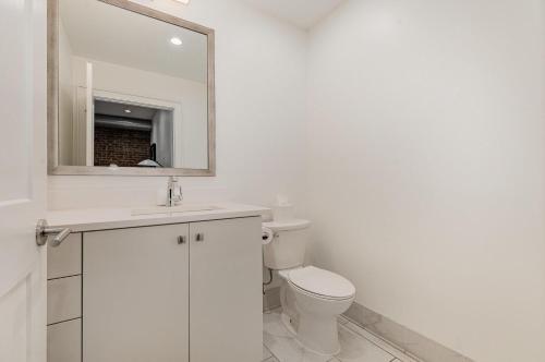 a white bathroom with a toilet and a mirror at The Saddlery - Encore - 1 Block to Broadway in Nashville