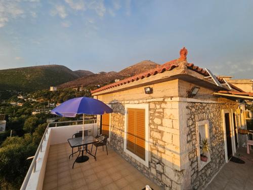 a patio with a table and an umbrella on a balcony at Ionian Sunset House in Piqeras