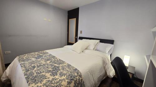 a bedroom with a white bed with a floral blanket on it at Freyja Café Bistró - Hostal Boutique in Bogotá