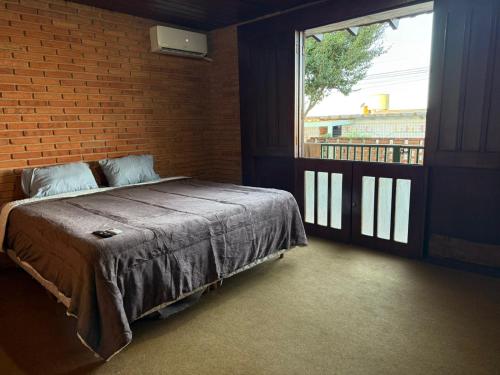 a bedroom with a bed and a large window at Suíte king com ar condicionado in Botucatu