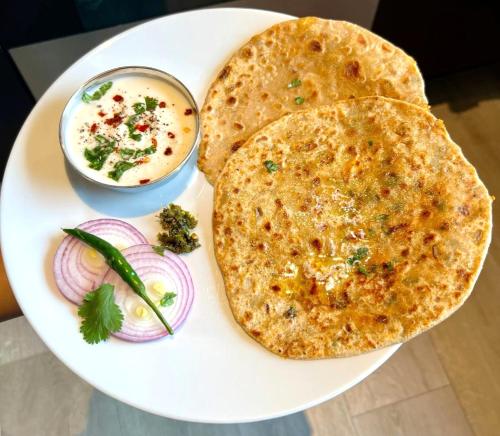 a plate with two naan bread and a bowl of dip at Worldwide Suites Near IGI Airport in New Delhi