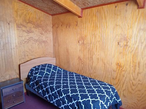 a bedroom with a bed and a wooden wall at cabaña milita in Chile Chico