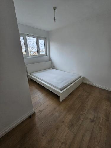 a white room with a bed and a window at Spacious room in London