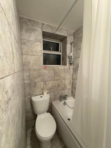 a bathroom with a toilet and a tub and a window at Jerryinn Rooms in London