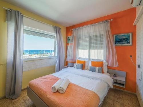 a bedroom with a bed with orange walls and a window at Breezot Yam in Nahariyya