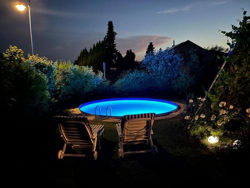 two chairs and a swimming pool at night at Wunderschöne, große Gartenwohnung mit 3 Schlafzimmern Nähe Kaufbeuren 