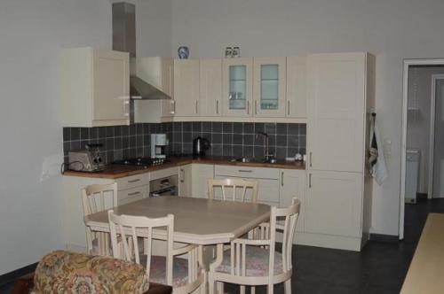 cocina con armarios blancos, mesa y sillas en Vino Grando Cottage en Odiliapeel