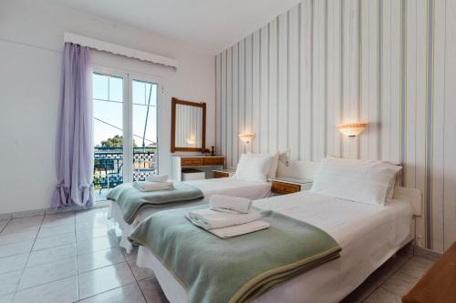 a hotel room with two beds and a window at Ionio Gastronomy Suites in Ammoudia