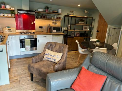 a living room with a couch and a kitchen at Beach hut seaside cottage in Sheringham