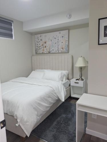 a white bedroom with a white bed and a lamp at Oxnard Villa in Winnipeg