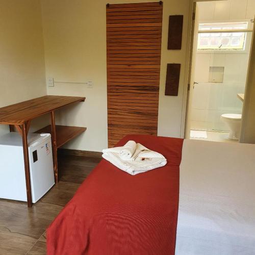 a room with a bed and a table and a sink at Casa Bon Voyage - Guesthouse in Paraty