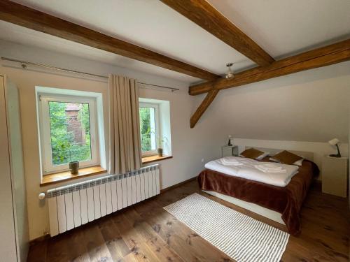 a bedroom with a bed and two windows at Stara Plebania in Pastewnik