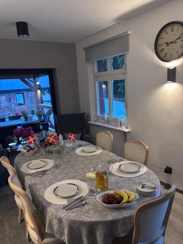 a dining room table with a clock on the wall at Osada Narost 37 in Chojna