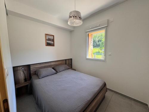 ein Schlafzimmer mit einem Bett und einem Fenster in der Unterkunft Appartement neuf T3 avec jardin au bord du lac in Génos