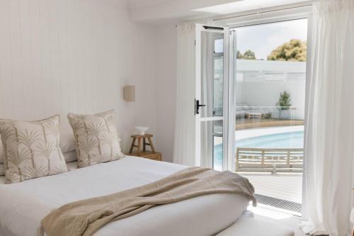 a white bedroom with a bed and a sliding glass door at Lynwood Luxe Mudgee in Mudgee