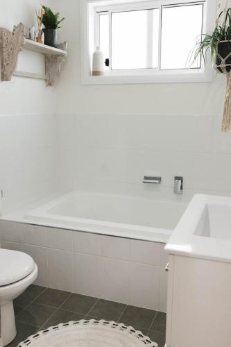 a white bathroom with a tub and a toilet at Lynwood Luxe Mudgee in Mudgee
