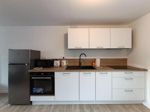 Una cocina con gabinetes blancos y un refrigerador de acero inoxidable. en Studio Saint Marc sur Mer, en Saint-Nazaire