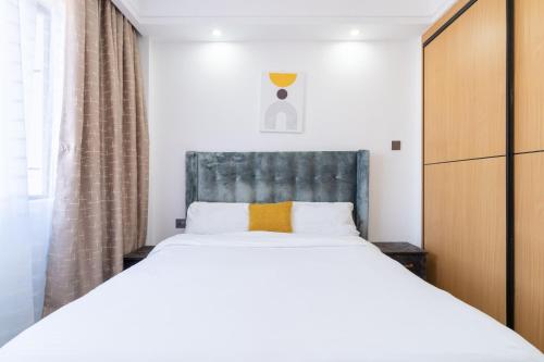 een slaapkamer met een groot wit bed met een grijs hoofdeinde bij Gatundu Heights in Nairobi
