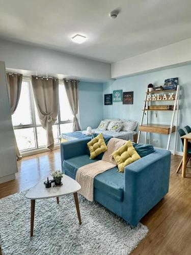 a blue couch with yellow pillows in a living room at Bleu Suite in Abreeza Place Davao City in Sampong