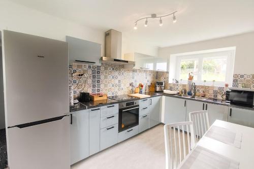 a kitchen with white cabinets and a table in it at La longère des cerisiers 