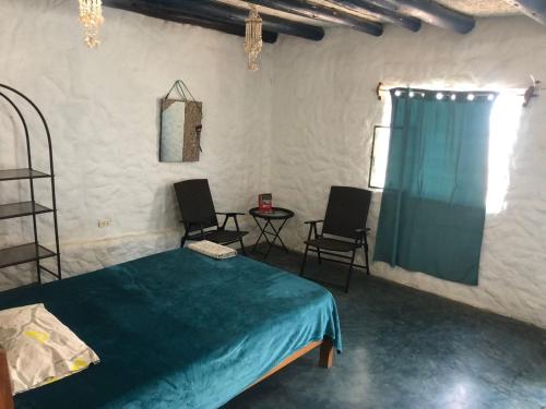a room with a bed and two chairs and a window at Huanchaco Surf Camp in Huanchaco