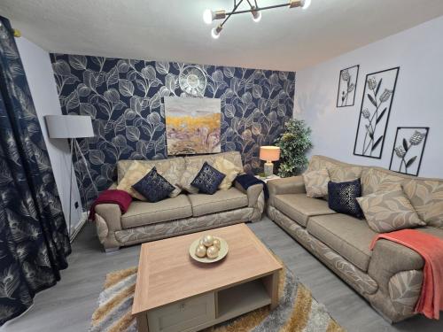 a living room with two couches and a table at Stylish and Comfortable Home in Beeston