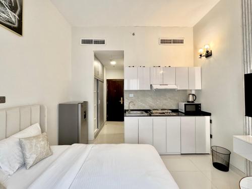 a bedroom with a white bed and a kitchen at Signature Vista Studio Apartment in Dubai