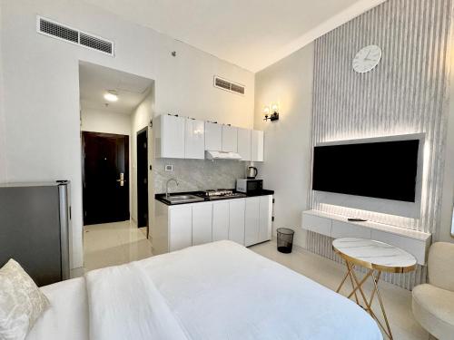 a white room with a bed and a kitchen at Signature Vista Studio Apartment in Dubai